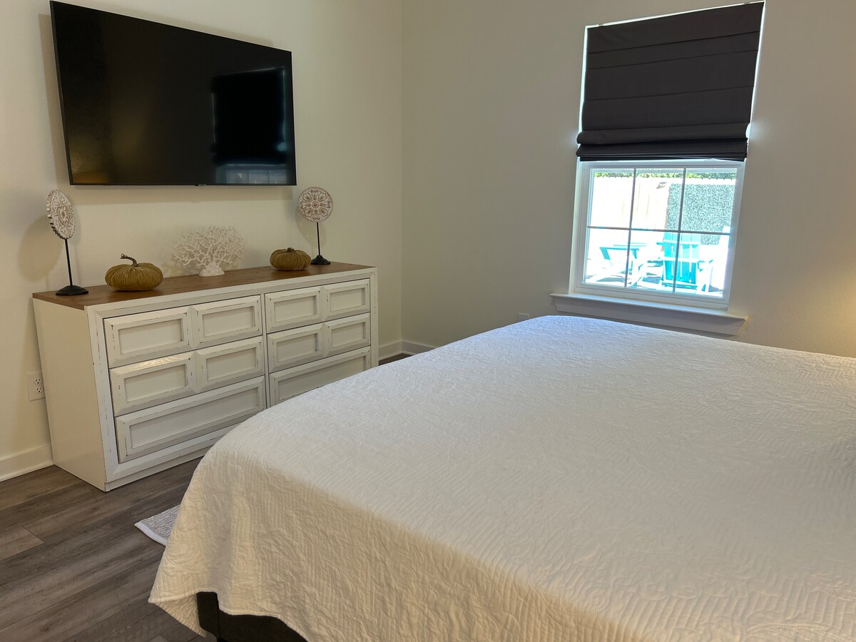 Primary bedroom with blackout shades and Samsung Smart TV at Auer House
